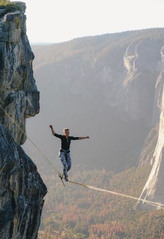 Woman walking a tightrope above a valley without fearing failure.