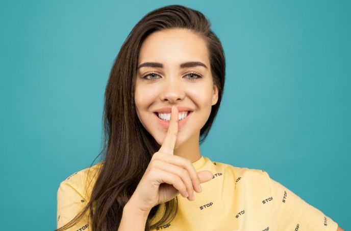 pexels-sound-on-3760945-min woman smiling with finger on mouth